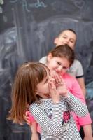 group of kids standing in front of chalkboard photo