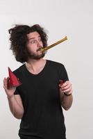 Portrait of a man in party hat blowing in whistle photo