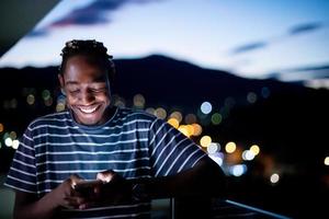 joven afro en la calle por la noche usando el teléfono foto