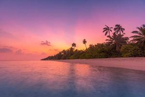 Palm trees on the tropical beach, amazing sunset, tropical island coast. Sun rays, dream romantic exotic beach landscape. Palm trees, calm lagoon sea horizon. photo