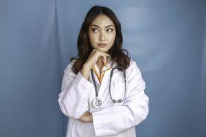 Young doctor woman over isolated background thinking an idea photo