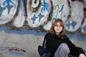 St. Petersburg, Russia, 06.01.2022. A teenage girl sits in an abandoned building painted with graffiti and smokes photo