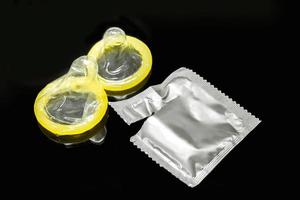 Condoms and opened package isolate on black background photo