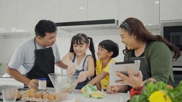 Happy family mom dad and kids siblings cooking together, parents teaching children son daughter cooking fresh vegetable salad and croissant prepare healthy food in modern kitchen interior together