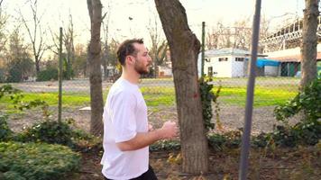 el atleta está corriendo en el parque. deportista corriendo en pista de jogging al atardecer en el parque. aspecto joven y atlético. video