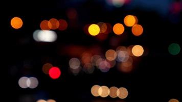 verschwommenes bokeh von autos im verkehr auf der straße bei nacht. abstraktes helles unscharfes farbiges bokeh. video