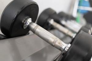 pararse con pesas. Sala de deportes y fitness. equipo de entrenamiento con pesas. juego de mancuernas negras, muchas mancuernas en el rack en el gimnasio deportivo foto