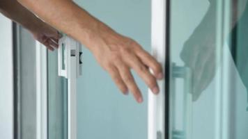 close-up da mão do homem fechando uma porta de vidro. video