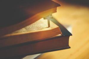 Closeup of wooden Christian cross necklace next to holy Bible photo