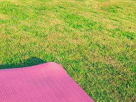 Pink yoga mat laid on green grass In the park in the evening there was a soft sunlight. The warm light tones are suitable for yoga exercises. photo