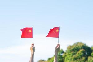 hand holding China flag on blue sky background. National Day of the People Republic of China, public Nation holiday Day and happy celebration concepts photo