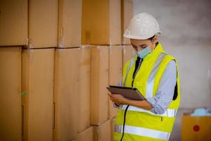 Factory engineer under inspection and checking quality production process on face mask manufacture  station by  wearing casual uniform and safety helmet in factory plantation. photo