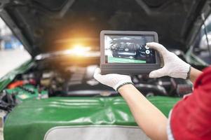 Professional mechanic and check car engine with computer diagnostic software.Expertise mechanic working in automobile repair garage. photo