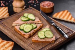 Delicious fresh sandwich with chicken liver pate with crispy toast, butter and cucumber photo