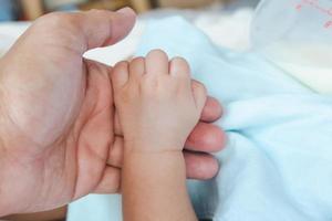 baby holding father's hand photo