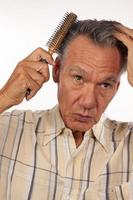 Mature man 60 plus combing his hair with a brush photo