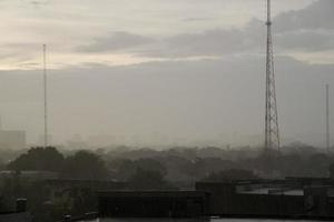 lluvia intensa de fondo que cae del cielo de la temporada de lluvias, silueta de árboles y edificios, tailandia tropical. foto