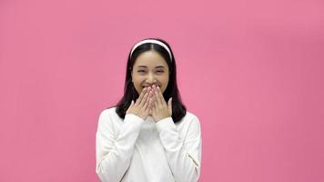 happy young woman Asian smiling and having good time, laughing, looking to side on pink background photo