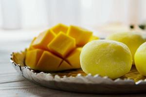Tasty dessert Mochi with mango fruit on wooden background, close up. photo