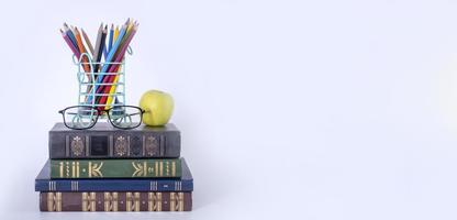 A stack of books, study guides, textbooks, glasses, and pencils in a text copy holder. photo