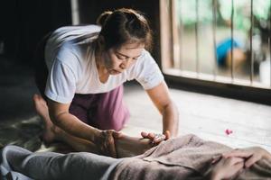 Massage and spa relaxing treatment of office syndrome using hot stone traditional thai massage style. Asain female masseuse doing foot massage treat stress for woman. photo