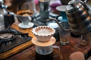 café por goteo, barista vertiendo agua en café molido con filtro foto