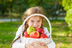 niña sosteniendo una cesta de manzanas foto