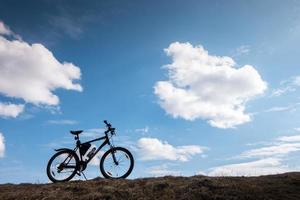 Bike silhouette in blue sky with clouds. symbol of independence and freedom photo