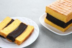 Spiku or Lapis Surabaya or Surabaya Layer Cake is a three-layer sponge cake with strawberry jam in between. Served in white plate, close up. photo