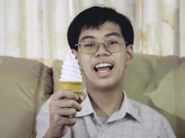 niño de asia niño sostenga helado de vainilla en cono de gofres feliz sonriendo y comiendo deliciosamente en verano con diversión y buen humor. foto