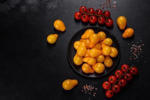 pequeños tomates amarillos en forma de pera en un plato de cerámica sobre una mesa de hormigón oscuro foto