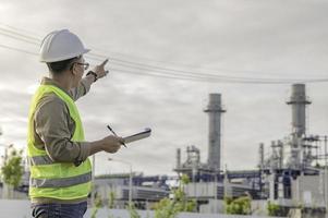 ingeniero petroquímico asiático que trabaja en la fábrica de la industria de la planta de refinería de petróleo y gas, el trabajador de la gente ingeniero controla el trabajo en la fabricación de la industria energética de la planta de energía foto