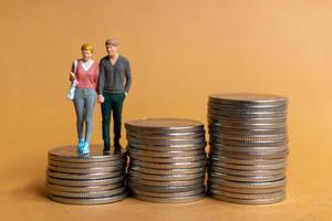 Miniature people, Happy couple standing on coins stack photo