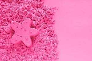 ink kinetic sand with starfish sand figure on light pink paper background with copy space. Early sensory education for children. Kids development concept. Leisure time on vacation. photo