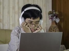 Preteen schoolboy wearing headphone to learning online watching class lesson looking at laptop computer to study. Distance and education learning stay at home. photo