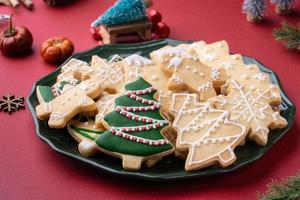 Close up of Christmas sugar cookies in a plate on red table background. photo