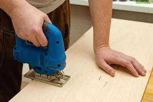 Image of a man hand using electric jigsaw photo