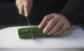 el chef está preparando pepino fresco para hacer el menú de cocina tradicional de Japón, rollo de sushi maki japonés que se sirve en un restaurante oriental, varios conceptos variados de comida saludable mezclada de lujo foto