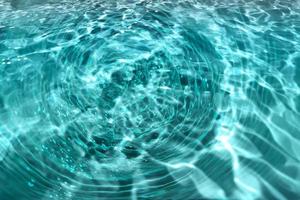 Defocus blurred transparent blue colored clear calm water surface texture with splashes and bubble. Trendy abstract nature background. Water wave in sunlight with copy space. Blue watercolor shining. photo