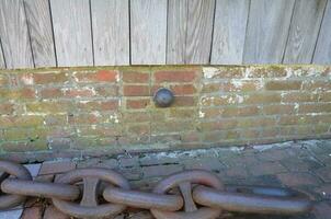 small iron cannonball stuck in side of brick building with metal chain photo