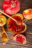 Rosh hashanah - jewish new year holiday concept. Bowl in the shape of an apple with honey, apples, pomegranates, shofar on wooden vintage background photo