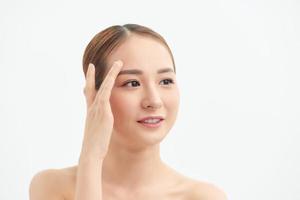 Attractive young Asian girl touching her face on white background photo