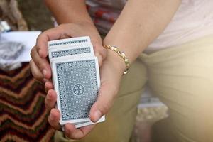 Paper cards number 5 holding in hands of woman who sitting and playing card with friend, soft and selective focus, freetimes and hobby activity at home concept. photo