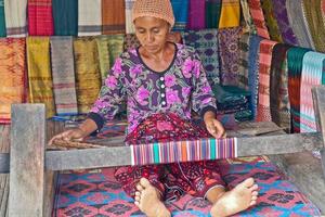 Sade Village, Lombok, Indonesia, June 2021- A woman weaves yarn to be used as sesek photo
