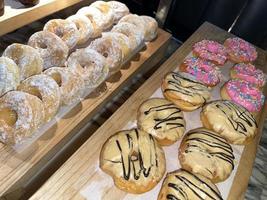 filas de deliciosos donuts frescos en la panadería, deliciosos donuts múltiples, donuts de enfoque selectivo foto