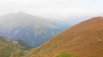 vista aérea de movimiento rápido hacia atrás mujer deportiva sola en el mirador del acantilado caminar explorar montañas en el fondo de la gama del cáucaso de otoño en racha, región georgiana. ruta de senderismo del lago udziro video