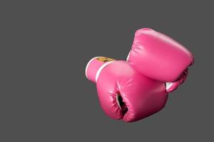 pink boxing gloves for girl and woman fight with copy space in dark background. photo