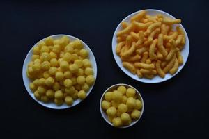 chips de maíz salados y con pimienta en un plato blanco. delicioso desayuno de chips de maíz sobre un fondo negro. foto