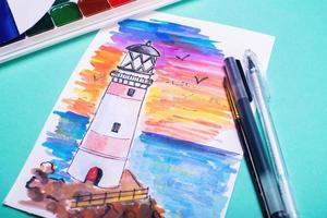 Lighthouse on coast of sea. Hand drawn beacon. Sketch with paints and pens on the table. photo