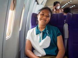 A woman wearing a mask is sitting by the window of an airplane. photo